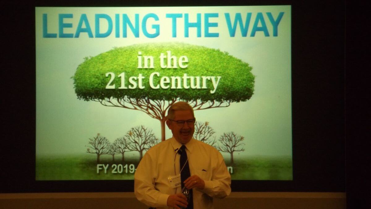 Image of speaker Kirk giving a talk about "Leading the way in the 21st Century"