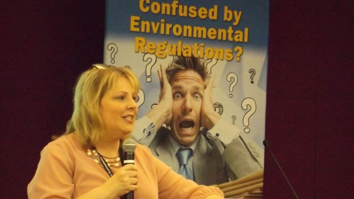 Image of speaker in front of  "Confused by Environmental Regulations" sign