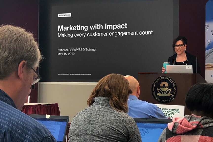 Image of speaker Julie giving a presentation about "Marketing with Impact"